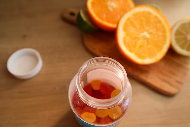 A jar of fruit snacks and freshly cut orange pieces