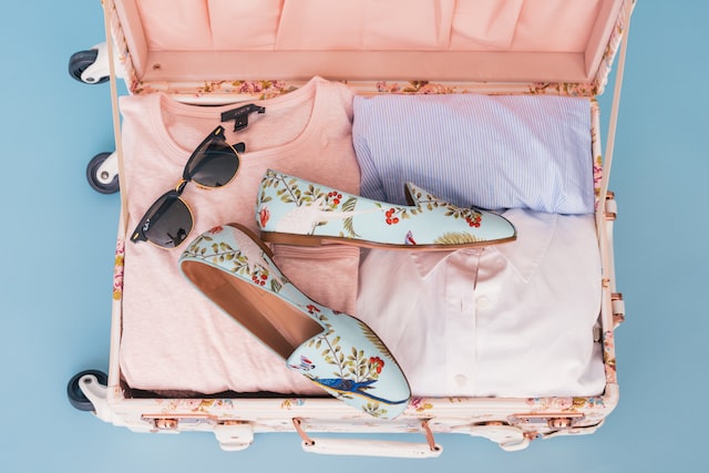 A suitcase with pastel color clothes and a pair of flats