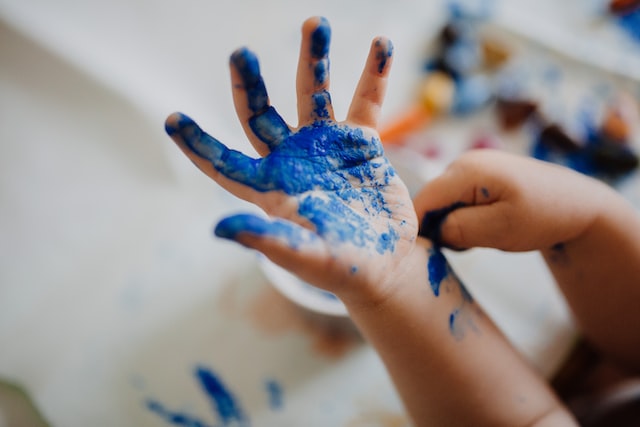 A child's hand colored in blue. They've been fingerpainting