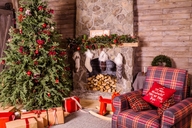 A room with an armchair, fireplace and a Christmas tree decorated for Christmas