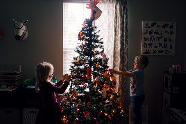 A boy and a girl decorating a Christmas tree