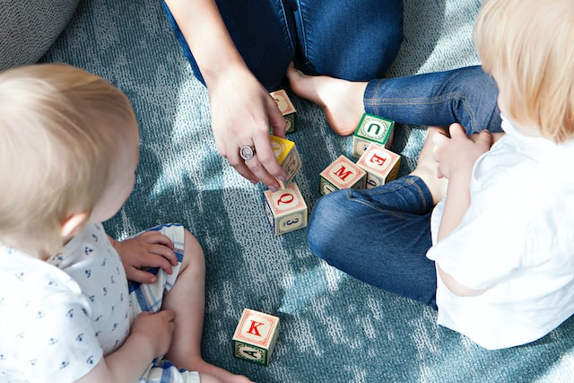 Kids exploring numbered wooden building blocks with their mother