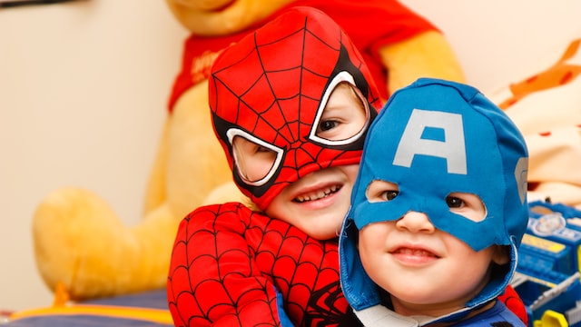 Two children dressed up in costumes at a birthday party. 